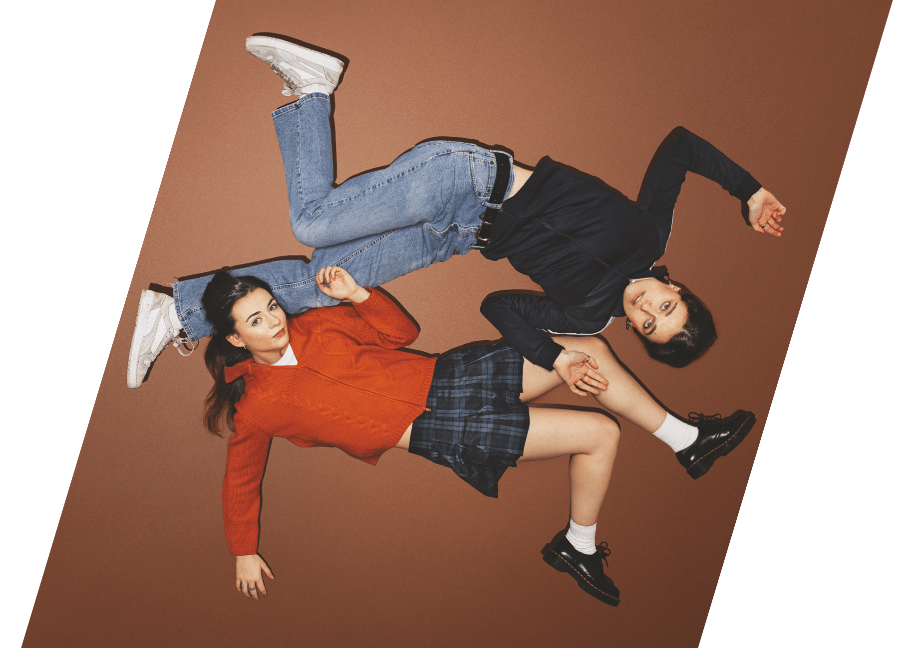 For Dolores image. Both actors lying flat on a burnt orange background, limbs laid out in different directions.
