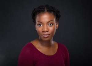 Esosa Ighodaro's headshot. She is wearing a maroon top and is pictured against a grey backdrop.